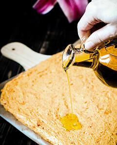 pouring olive oil over focaccia