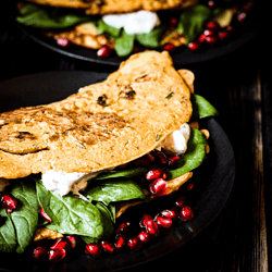 Tasty vegan omelette based on chickpea flour and tofu, with fresh spinach, vegan sour cream and pomegranate seeds